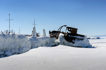 Old iron ship covered with ice at lake in winter