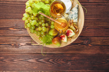 Grape, cheese, figs and honey with wine on wooden table