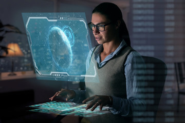 Close up of a beautiful girl with glasses while she is working with a futuristic computer with...