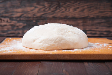 Dough on wooden background, fresh pastry concept.