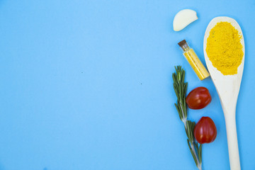 Cooking Hot Spicy Food Concept. Dry spices in wooden spoon, herbs and chili pepper on a light blue backhround