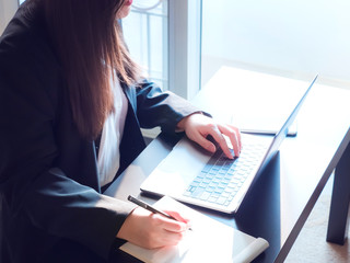 woman power and industry 4.0 concept from beauty asian business woman hand in black suit use her modern laptop check database and record in blank paper