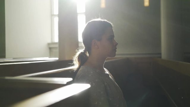 Woman praying in dark cathedra,l Crop side view of young woman with eyes closed in sun shine