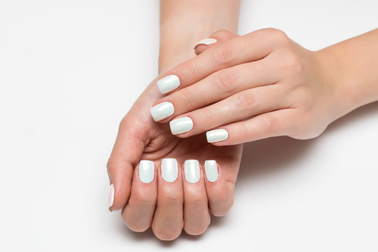 Wedding white pearl manicure on short square nails on a white background close-up.
