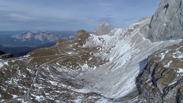 Aerial - Flying above mountain road next to scree slope with some snow