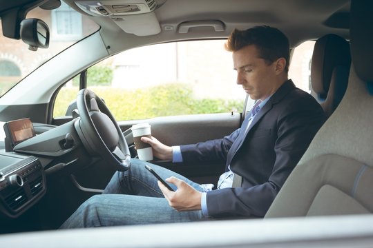 Businessman using mobile phone while driving car