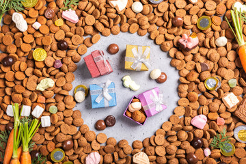Dutch holiday Sinterklaas background with gifts, pepernoten, traditional sweets strooigoed and carrots for Santa's horse. Flat lay.