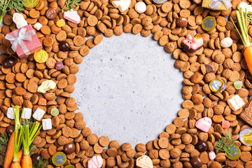 Dutch holiday Sinterklaas background with gifts, pepernoten, traditional sweets strooigoed and carrots for Santa's horse. Flat lay with copy space.