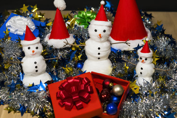 Christmas. Toy grandfathers Frost and Christmas hats. Gift boxes with Christmas ornaments. Garlands. Wooden table.