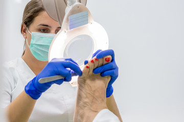 Female chiropodist, attending elder in a clinic and performing podiatric treatments