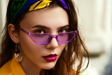 Outdoor close up portrait of young beautiful fashionable woman wearing trendy violet color...
