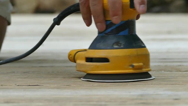 Sanding wooden deck with electric sander