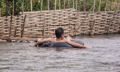 A man in a river sitting in a rubber ring.