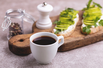 Avocado toasts with coffee on gray slate background