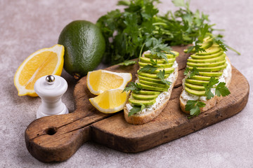 Avocado toasts and ingredients on gray slate background