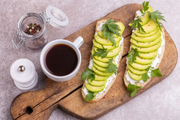 Avocado toasts with coffee on gray slate background