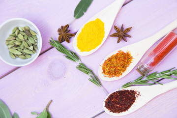Cooking Hot Spicy Food Concept. Dry spices,beans and herbs in plastic cup, glass jar with cork and wooden spoon, purple wooden background