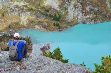  Altai territory, Ust-Koksinsky district, Russia. Man sitting on a cliff above the lake Kuiguk (Kuyguk) in Altai