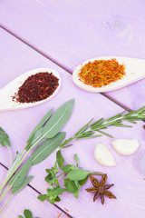 Cooking Hot Spicy Food Concept. Dry spices,beans and herbs in plastic cup, glass jar with cork and wooden spoon, purple wooden background