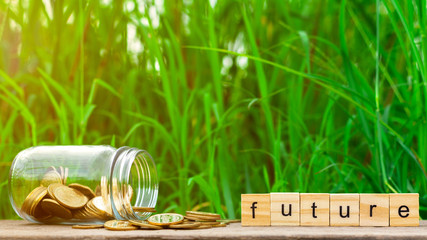 future word and a pile of golden coins on wooden table. - Concept of saving money for future.