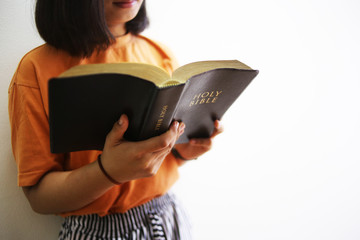 The woman is reading the biblical book.