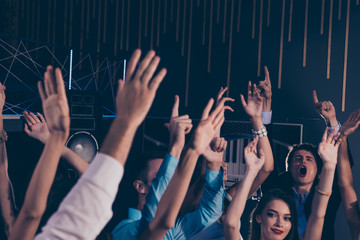Cheerful excited glad audience with raised hands at music festiv