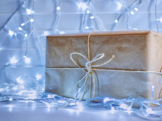 A large gift box is wrapped in kraft paper and bandaged with string. On a wooden background there...