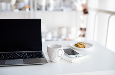 Modern white office, designer handmade cup with coffee, smartpho