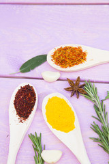 Cooking Hot Spicy Food Concept. Dry spices,beans and herbs in plastic cup, glass jar with cork and wooden spoon, purple wooden background