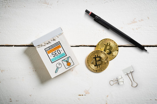 Abreißkalender mit SEO Symbolen auf Holzuntergrund mit Bitcoin Münzen