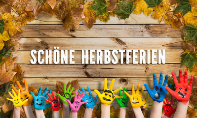 in bunten Farben angemalte Kinderhände herbstlich dekoriertem Holzschild und der Aufschrift...