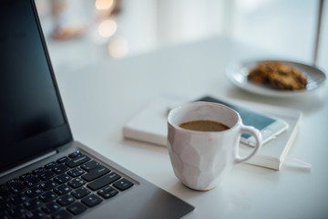 Modern white office, designer handmade cup with coffee, smartpho