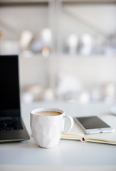 Modern white office, designer handmade cup with coffee, smartpho