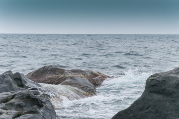 Large stones, boulders on the seashore, the ocean. Overcast weather on vacation.