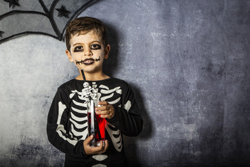 Little kid in a skeleton costume drinking  fake blood on Halloween