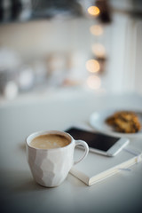 Modern white office, designer handmade cup of coffee, smartphone