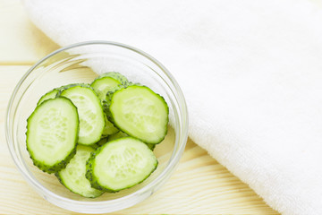 Cucumber home spa and hair care concept. Sliced cucumber, bottles of oil, soap, jar of mask, bathroom towel. White board background