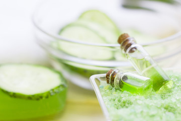 Cucumber home spa and hair care concept. Sliced cucumber, bottles of oil, soap, jar of mask, bathroom towel. White board background