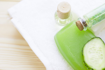 Cucumber home spa and hair care concept. Sliced cucumber, bottles of oil, soap, jar of mask, bathroom towel. White board background
