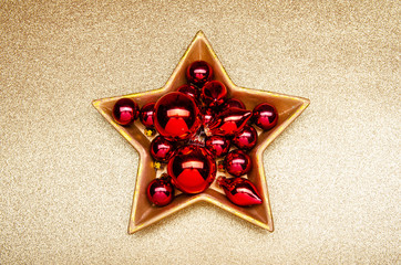 red christmas decoration in a golden star-shaped bowl on a golden  background