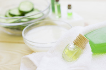 Cucumber home spa and hair care concept. Sliced cucumber, bottles of oil, jar of mask, bathroom towel. White board background