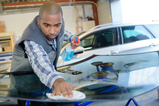 Garage worker polishing replacement windscreen