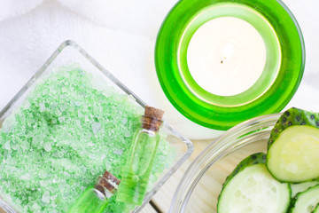 Cucumber home spa and hair care concept. Sliced cucumber, bottles of oil, sea salt, bathroom towel. White board background