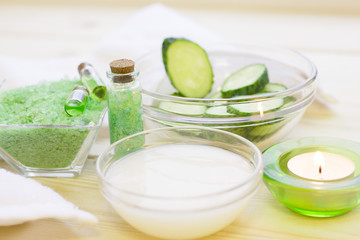Cucumber home spa and hair care concept. Sliced cucumber, bottles of oil, sea salt, bathroom towel. White board background