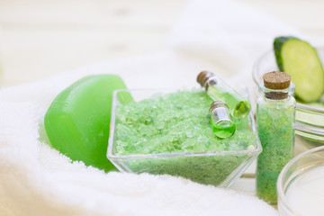 Cucumber home spa and hair care concept. Sliced cucumber, bottles of oil, sea salt, bathroom towel. White board background
