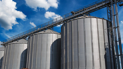 Steel Grain Silos Against Blue Sky With White Clouds