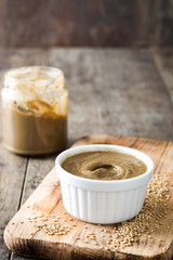 Tahini and sesame seeds on wooden table. 