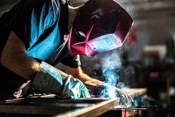 Industrial welder working with steel pipes – sparks and smoke during welding process