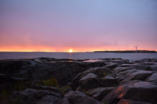 A beautiful combination of a golden sunset, turbines and rocky shore. In Kallo Island, Pori, Finland.