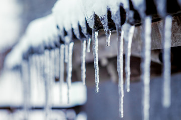 Icicles that hang from the roof of the house. Warm winter day_ - obrazy, fototapety, plakaty